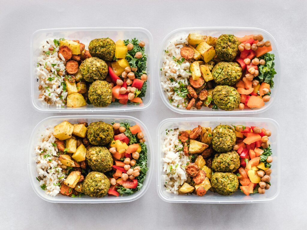Colorful meal prep containers with falafel, chickpeas, rice, and vegetables for a healthy lifestyle. Meal Prepping in Malaysia