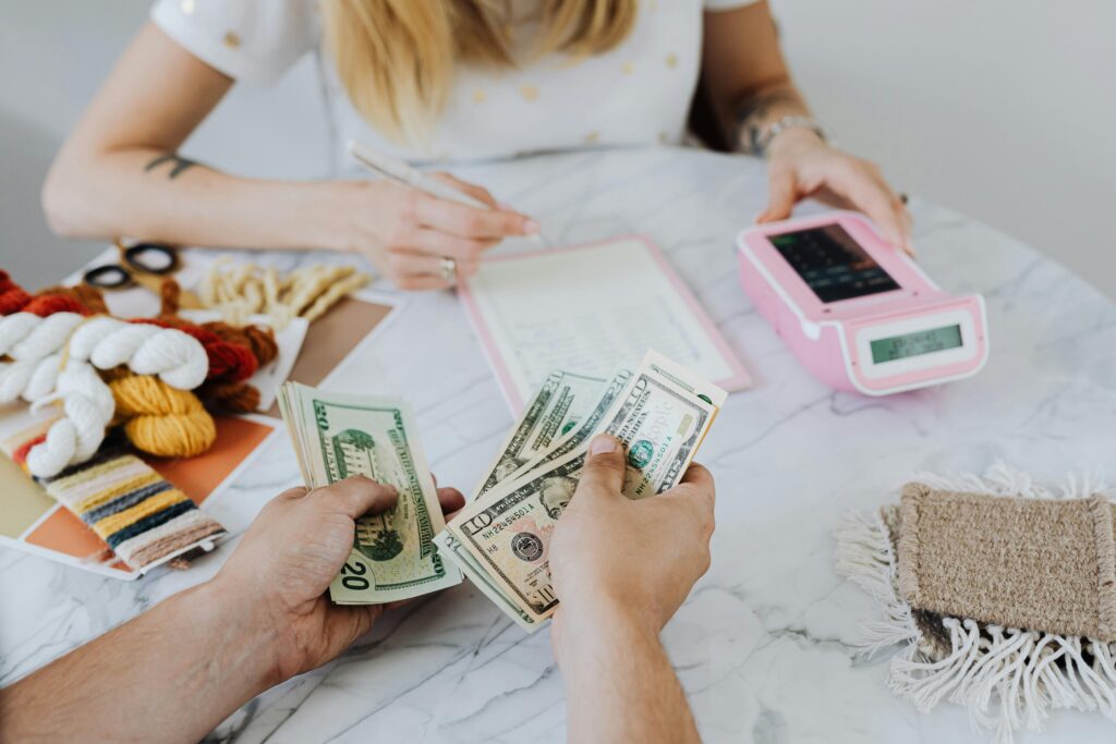 Two people handling cash and budgeting with a calculator and notebook at a table. How to Save Money Fast