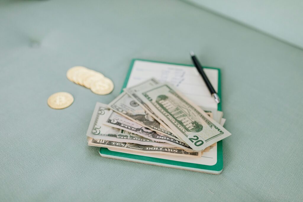 Close-up of American dollar bills and coins on a journal with a pen, representing budget planning.
