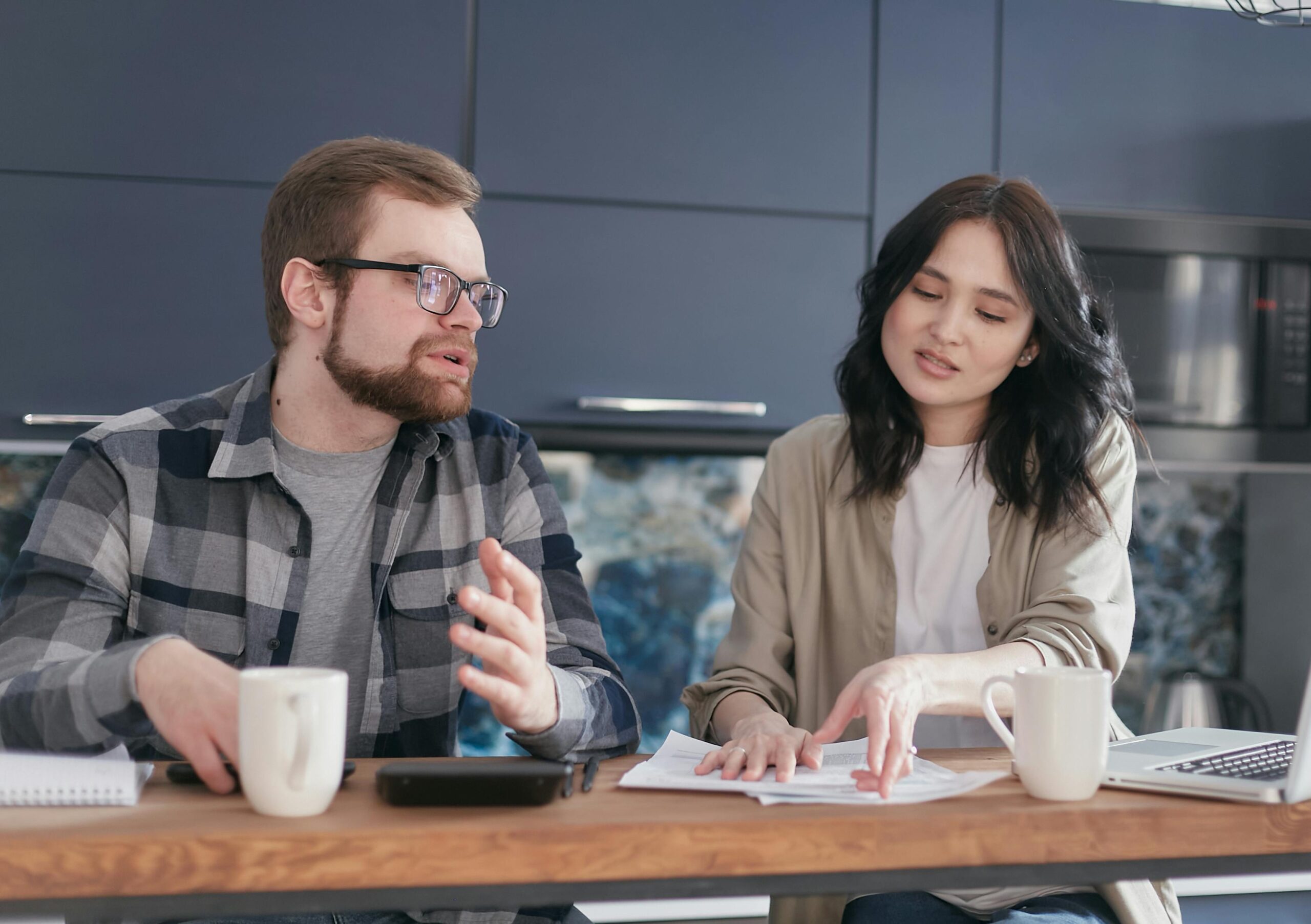 A young couple discusses financial documents at a cozy home setting, expressing concern.