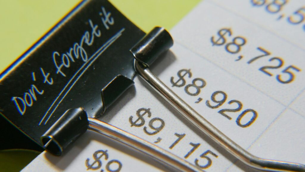 Close-up image showcasing a binder clip on a detailed financial report with highlighted amounts. Manage Your Money Efficiently