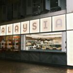 Chef preparing food in a modern urban food hall in Malaysia.