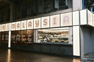 Chef preparing food in a modern urban food hall in Malaysia.