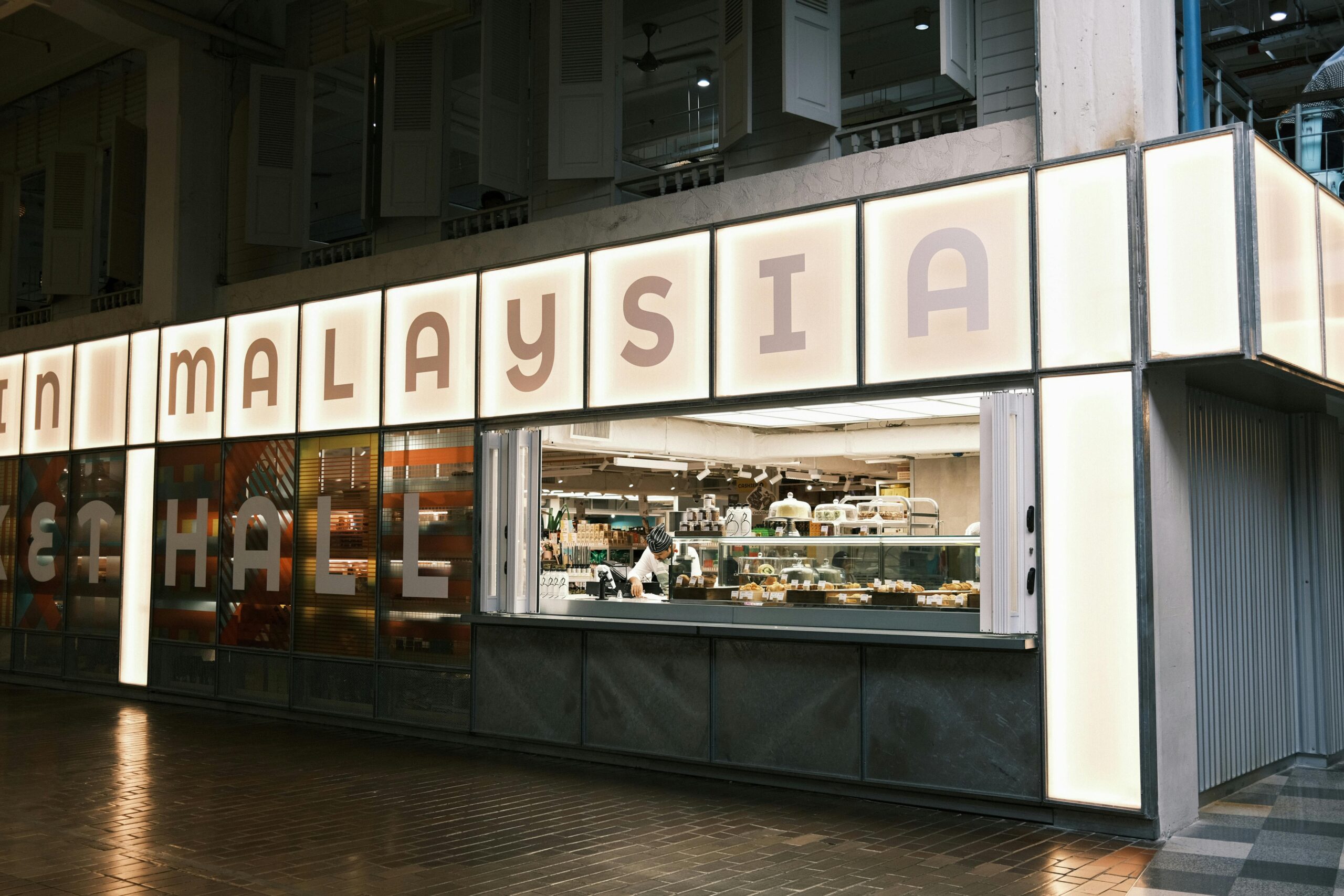 Chef preparing food in a modern urban food hall in Malaysia.