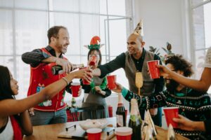 Group of friends enjoying a festive holiday party indoors with drinks and laughter.