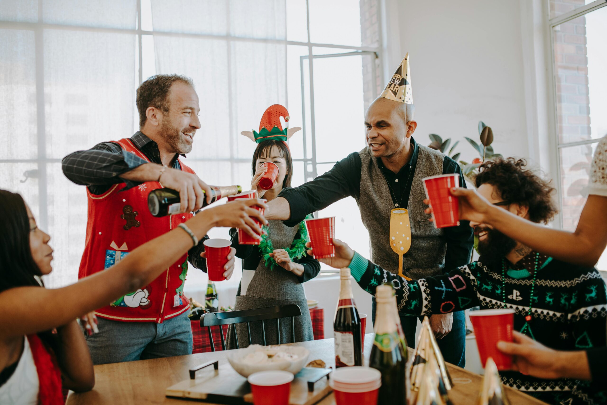 Group of friends enjoying a festive holiday party indoors with drinks and laughter.