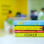 Colorful stack of popular business books on a desk in an office environment, blurred background.