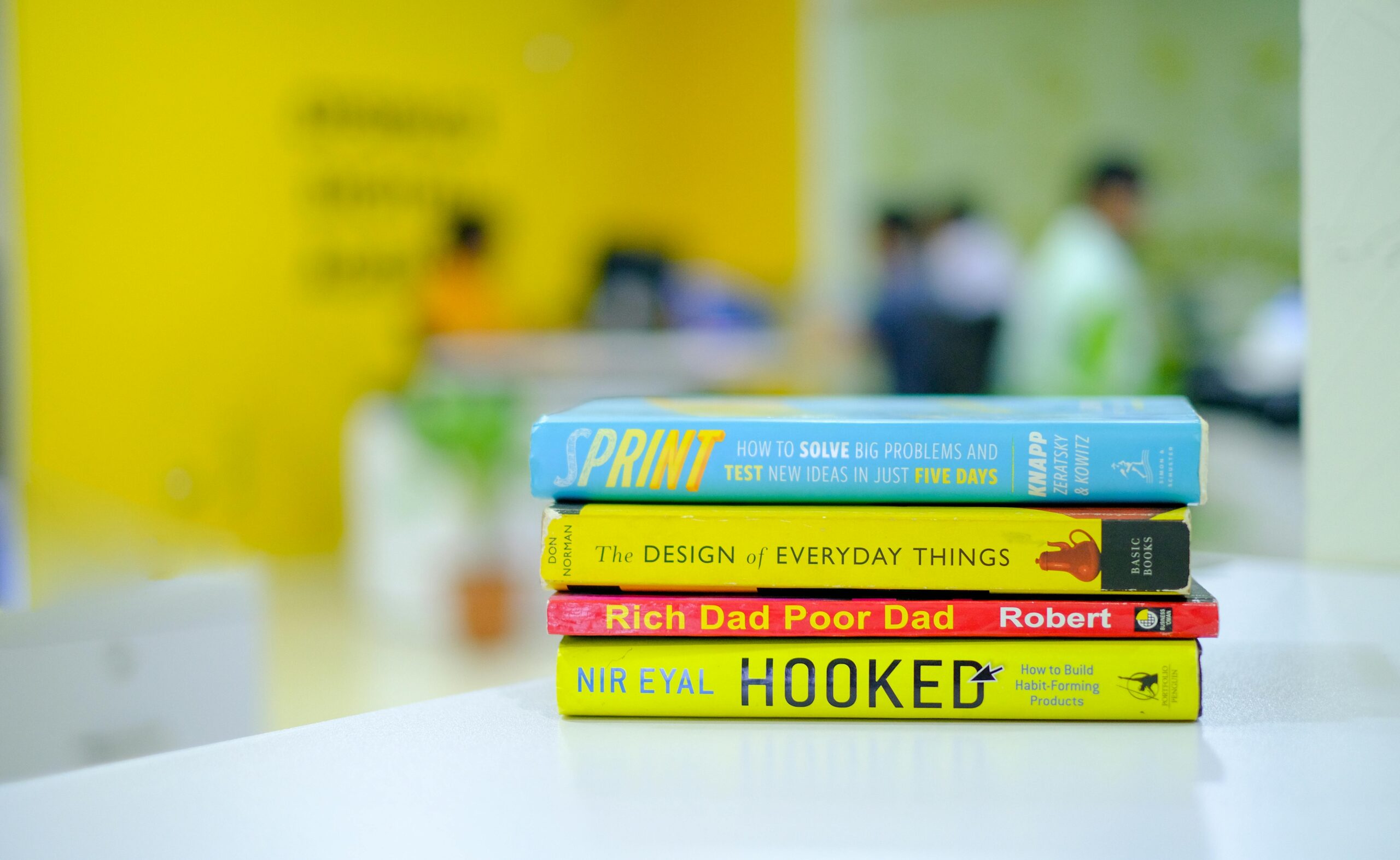 Colorful stack of popular business books on a desk in an office environment, blurred background.